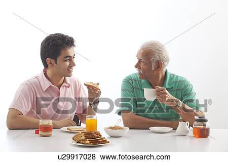 Grandfather and grandson eating breakfast View Large Photo Image Stock Photo - Grandfather and grandson eating breakfast. Fotosearch