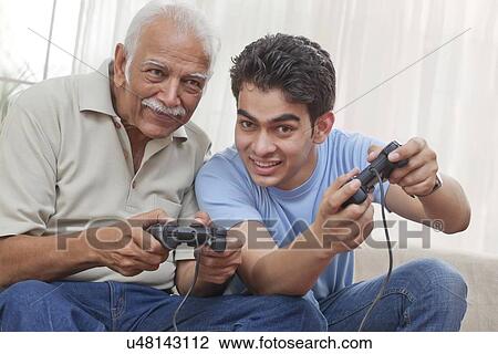 Stock Image - Grandfather and grandson playing video game. Fotosearch