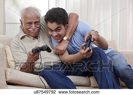 Stock Image - Grandfather and grandson playing video game. Fotosearch