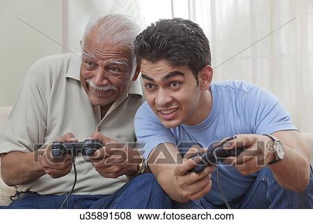 Grandfather and grandson playing video game View Large Photo Image Stock Photo - Grandfather and grandson playing video game. Fotosearch