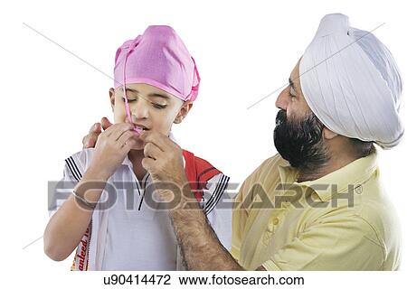 Stock Image - Grandfather helping grandson tie a turban . Fotosearch