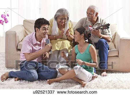Stock Photo - Grandfather playing the guitar with grandmother and grandchildren singing. Fotosearch