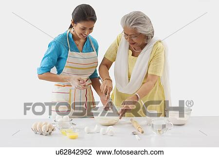 Stock Image - Grandmother and granddaughter working in the kitchen. Fotosearch