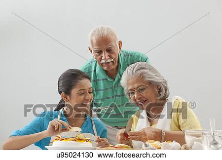 Grandmother and granddaughter working in the kitchen while grandfather looks on View Large Photo Image Stock Image - Grandmother and granddaughter working in the kitchen while grandfather looks on. Fotosearch