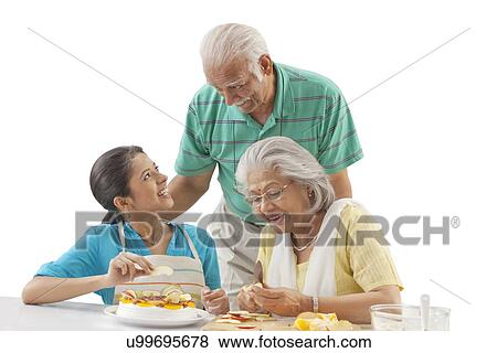 Grandmother and granddaughter working in the kitchen while grandfather looks on View Large Photo Image Stock Photo - Grandmother and granddaughter working in the kitchen while grandfather looks on. Fotosearch
