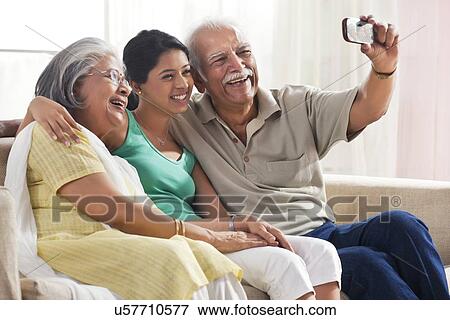 Stock Photo - Grandparents and granddaughter taking a photograph of themselves. Fotosearch