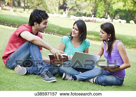 Stock Photo - Group of three friends sitting in lawn . Fotosearch