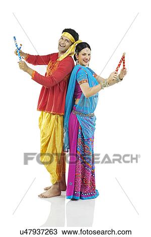 Stock Image - Gujarati couple performing dandiya dance . Fotosearch