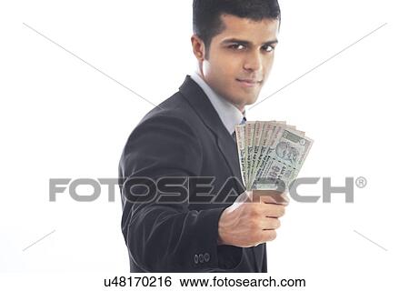Stock Photograph - Handsome business man holding Indian currency over white background . Fotosearch