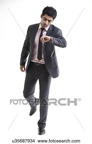 Handsome businessman checking time over white background View Large Photo Image Picture - Handsome businessman checking time over white background . Fotosearch