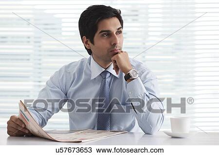 Handsome male executive in deep thought with newspaper at office View Large Photo Image Stock Image - Handsome male executive in deep thought with newspaper at office . Fotosearch