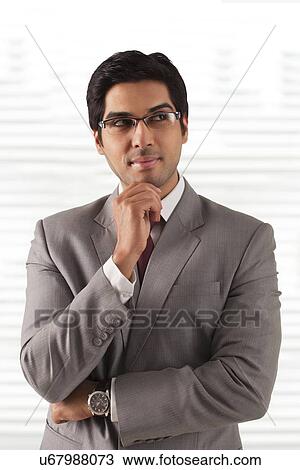 Handsome young businessman thinking at office View Large Photo Image Stock Image - Handsome young businessman thinking at office . Fotosearch