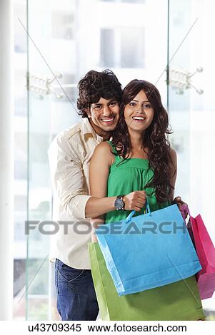 Stock Photography - Handsome young couple smiling while shopping . Fotosearch