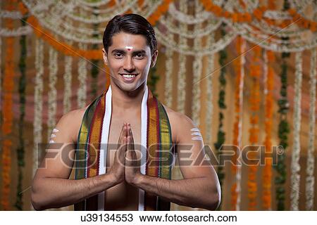 Stock Image - Handsome young groom standing with flower decoration in background . Fotosearch