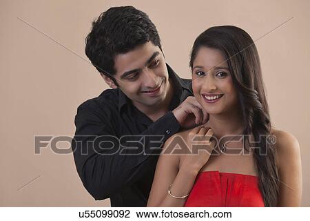 Handsome young man placing necklace on woman's neck View Large Photo Image Stock Image - Handsome young man placing necklace on woman's neck . Fotosearch