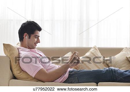 Stock Image - Handsome young man relaxing while listening to music . Fotosearch