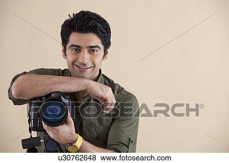 Handsome young man with digital camera over colored background View Large Photo Image Stock Photo - Handsome young man with digital camera over colored background . Fotosearch