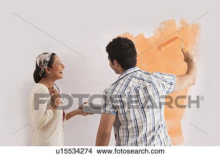 Happy beautiful woman looking at man while painting wall View Large Photo Image Picture - Happy beautiful woman looking at man while painting wall . Fotosearch