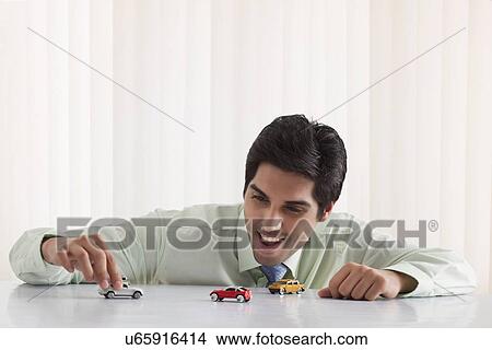 Happy businessman playing with model car View Large Photo Image Picture - Happy businessman playing with model car . Fotosearch