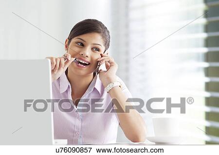 Stock Photo - Happy businesswoman at her desk using cell phone . Fotosearch