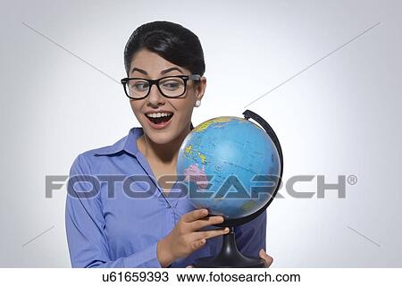 Happy businesswoman looking at globe over gray background View Large Photo Image Stock Image - Happy businesswoman looking at globe over gray background. Fotosearch