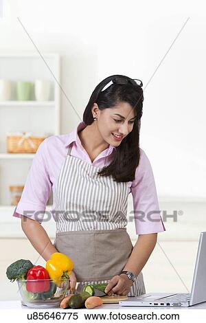 Happy businesswoman looking at laptop while cooking in kitchen View Large Photo Image Stock Photography - Happy businesswoman looking at laptop while cooking in kitchen. Fotosearch