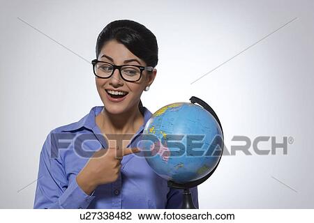 Happy businesswoman pointing at globe against gray background View Large Photo Image Stock Image - Happy businesswoman pointing at globe against gray background. Fotosearch