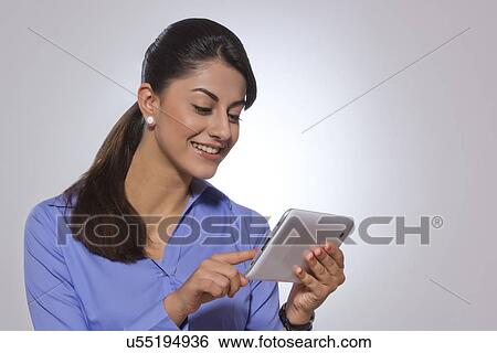 Stock Photograph - Happy businesswoman using digital tablet over gray background. Fotosearch