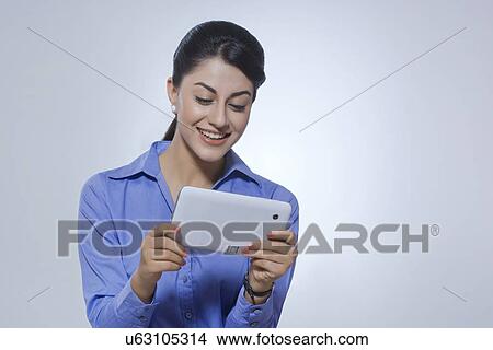 Happy businesswoman using tablet PC over gray background View Large Photo Image Picture - Happy businesswoman using tablet PC over gray background. Fotosearch