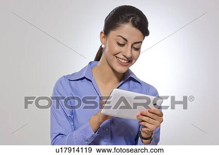 Happy businesswoman using tablet computer over gray background View Large Photo Image Stock Photo - Happy businesswoman using tablet computer over gray background. Fotosearch