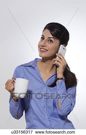 Happy businesswoman with coffee mug using phone over gray background View Large Photo Image Stock Photo - Happy businesswoman with coffee mug using phone over gray background. Fotosearch