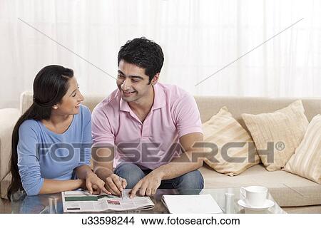 Picture - Happy couple smiling while solving puzzle at home . Fotosearch