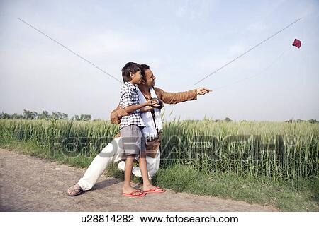 Happy father and son flying a kite in field View Large Photo Image Stock Image - Happy father and son flying a kite in field . Fotosearch