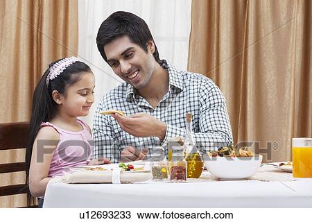Happy father feeding his cute daughter a piece of pizza at restaurant View Large Photo Image Stock Image - Happy father feeding his cute daughter a piece of pizza at restaurant . Fotosearch