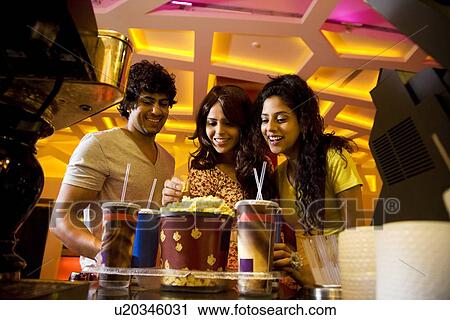 Happy friends smiling with bucket of popcorn and soft drink View Large Photo Image Stock Image - Happy friends smiling with bucket of popcorn and soft drink . Fotosearch
