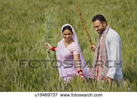Stock Photo - Happy Indian couple gliding through wheat field . Fotosearch