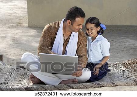 Stock Image - Happy Indian father and daughter using laptop . Fotosearch