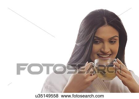 Happy thoughtful young woman holding tea cup View Large Photo Image Stock Photo - Happy thoughtful young woman holding tea cup . Fotosearch