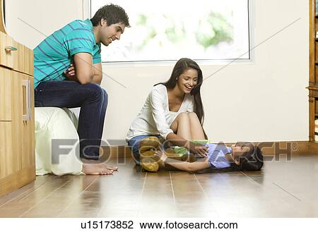 Happy woman playing with daughter while man sitting besides View Large Photo Image Stock Image - Happy woman playing with daughter while man sitting besides . Fotosearch