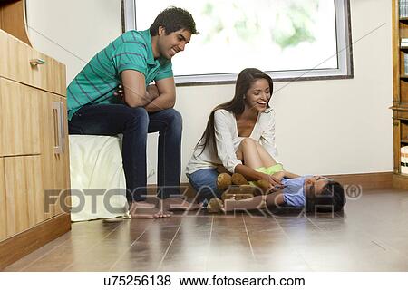 Happy woman playing with daughter while man sitting besides View Large Photo Image Stock Photo - Happy woman playing with daughter while man sitting besides . Fotosearch