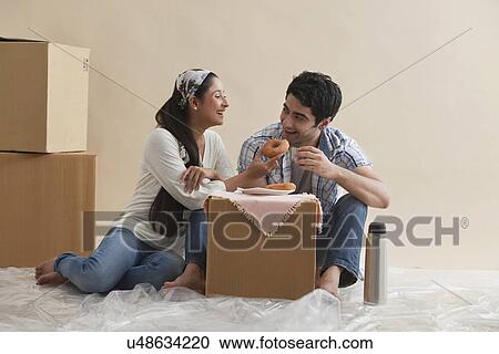 Stock Image - Happy young couple eating together at new home . Fotosearch