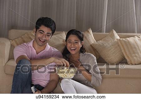 Picture - Happy young couple enjoying while watching TV at home . Fotosearch