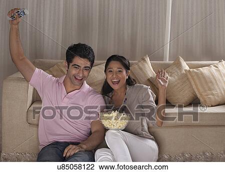 Happy young couple enjoying while watching TV at home View Large Photo Image Stock Image - Happy young couple enjoying while watching TV at home . Fotosearch