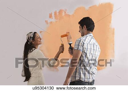 Happy young couple enjoying while painting their home View Large Photo Image Stock Image - Happy young couple enjoying while painting their home . Fotosearch