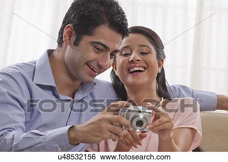 Stock Photograph - Happy young couple enjoying while looking at digital camera . Fotosearch
