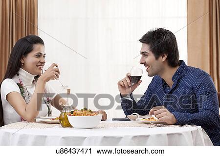 Stock Image - Happy young couple having wine at restaurant . Fotosearch