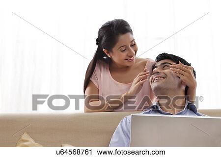 Stock Image - Happy young couple looking at each other with laptop . Fotosearch