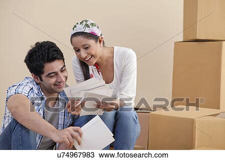 Happy young couple looking at photographs together at new home View Large Photo Image Stock Image - Happy young couple looking at photographs together at new home . Fotosearch