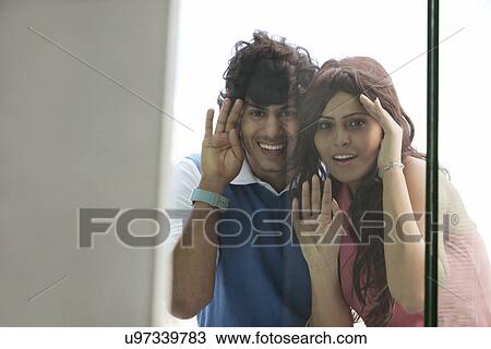Happy young couple peeking through window together View Large Photo Image Stock Image - Happy young couple peeking through window together . Fotosearch