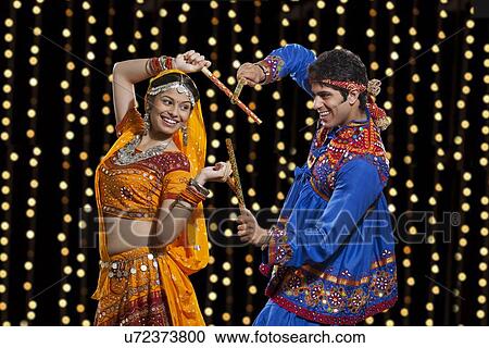 Happy young couple performing Dandiya Raas against neon lights View Large Photo Image Stock Image - Happy young couple performing Dandiya Raas against neon lights. Fotosearch